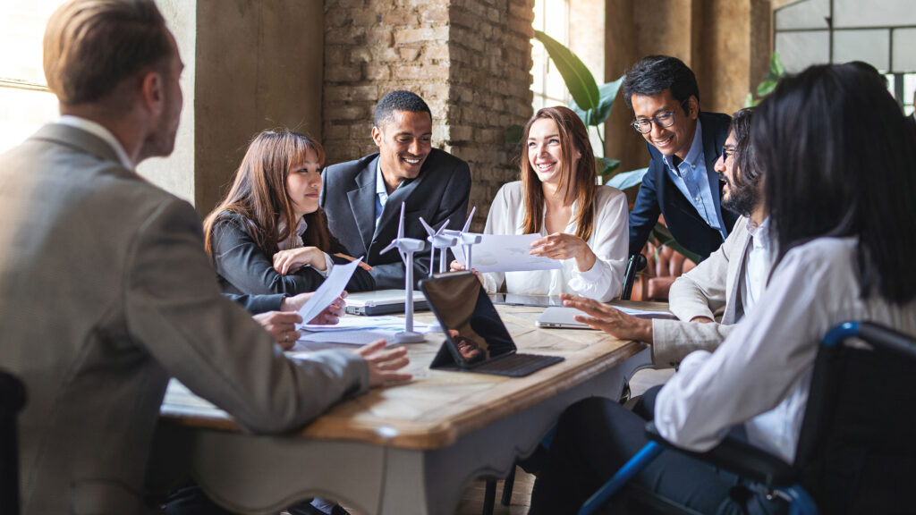 Team of men and women sat around a table in an office discussing net zero terms